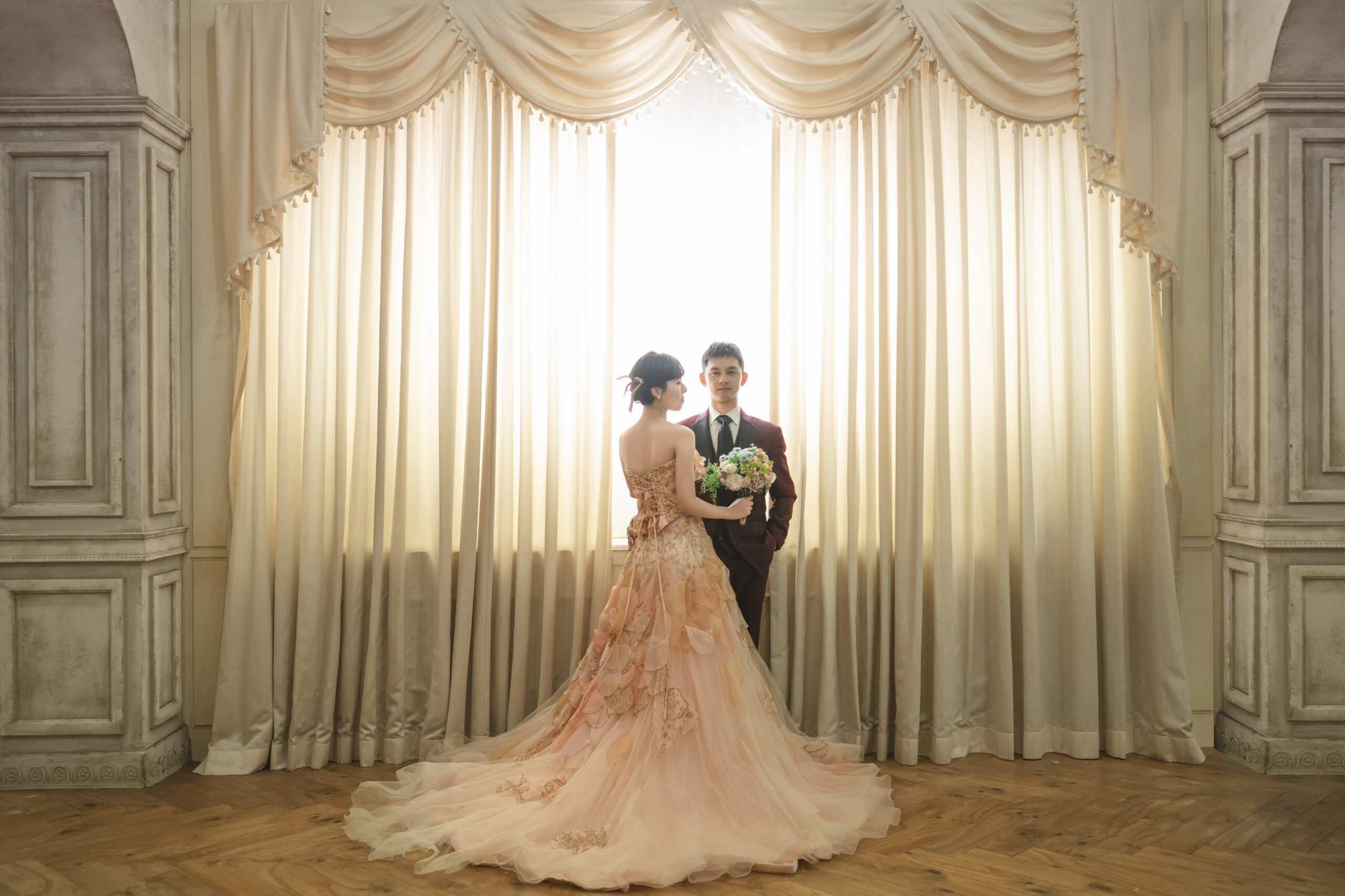 ドレスの裾が美しく広がる新郎新婦のドラマチックなウェディングフォト